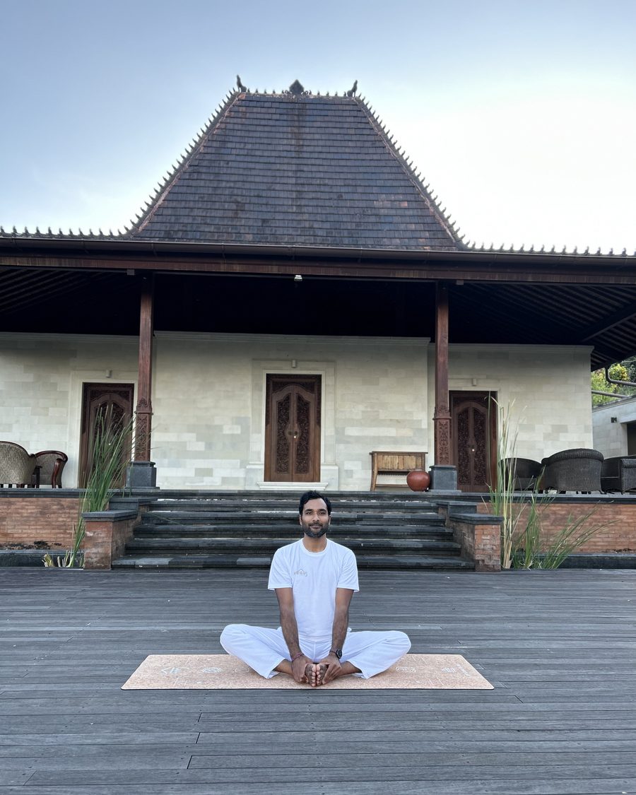 Mayank Rajput seated in meditation at a traditional pavilion, embodying Soul Light Yoga's roots